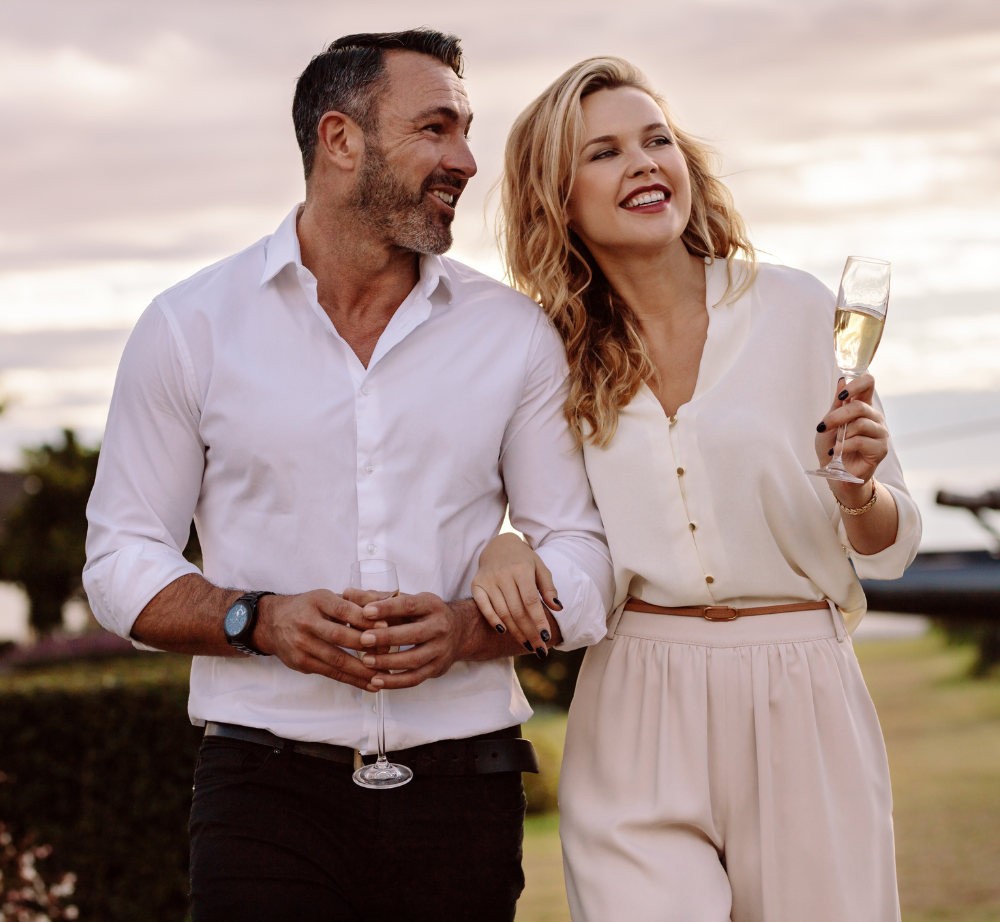 Pareja paseando, bien vestidos. Ella sujeta una copa de champaña mientras hablan y sonríen