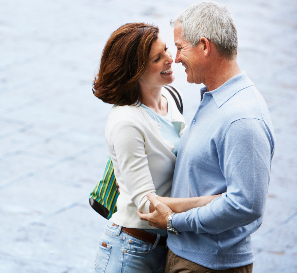 Pareja en una plaza abrazados y sonriendo